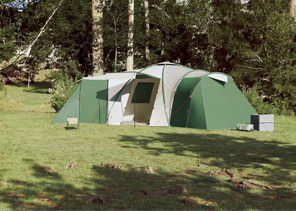 Голяма семейна палатка с къмпинг оборудване сред природата.