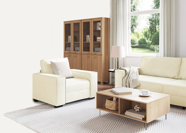 Бял 2-местен диван с възглавници и одеяло в закрито помещение.